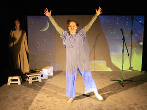 Zwei Frauen auf einer Bühne, eine tanzt, die andere singt. Bühnenbild mit Sterne und Mond und Himmel.