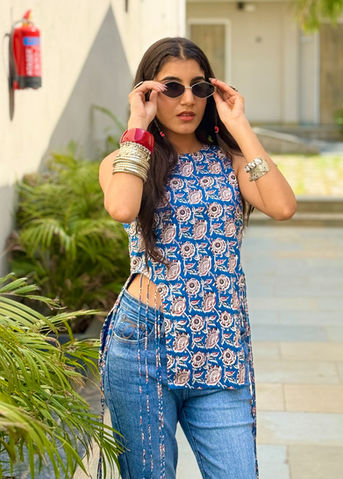 Young woman in blue patterned top, jeans, and sunglasses