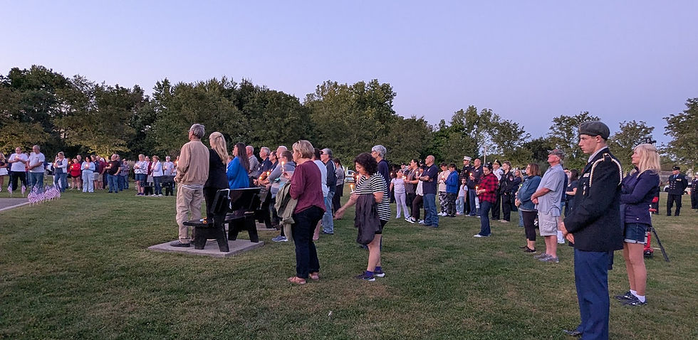 Field full of Patriots - with Councilman John Stegenga at left and Legislator Kathy Stegenga to his right. in front of the black bench.