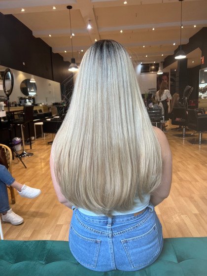Waist-length yellow/orange hair transformed to natural ash blonde with soft medium layers, showcasing a smooth blend from natural black roots for a low-maintenance look.