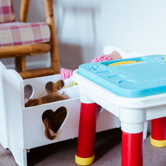 White doll bed with heart-shaped cutouts in a speech therapy play area.