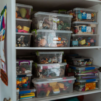 Shelf filled with plastic containers of therapy toys and materials in a speech therapy practice.