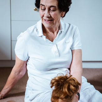 Senior speech therapist in a white polo shirt holding a doll during a therapy session.