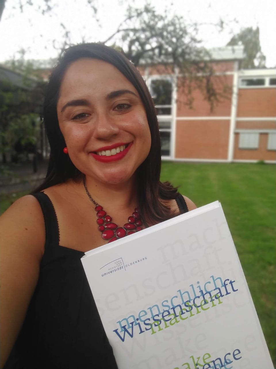 Young woman taking a selfie holding her diploma and smiling.