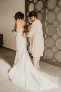 mother of the bride zipping daughters wedding gown