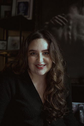 Smiling woman with long wavy hair, in a black shirt, posing for portrait