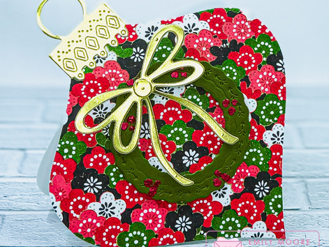 Red & green ornament-shaped greeting card with green wreath and gold bow on white background