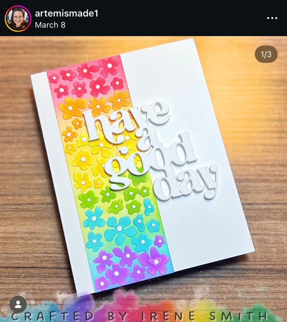 A card with rainbow flowers and white text saying "have a good day" on a wooden surface. Text at bottom: "Crafted by Irene Smith."