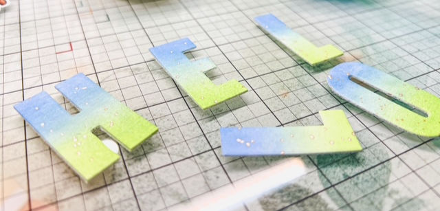Close-up of ombre ink-blended HELLO letters with gold spatter