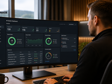 En mann ved skrivebordet ser på dashbordet for AV-systemet – med enhetstatistikk, alarmer og grafer – på en bredskjerm på et moderne kontor; AV SIGNAGE-logo.
