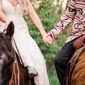a couple holding hands while sitting on their horses