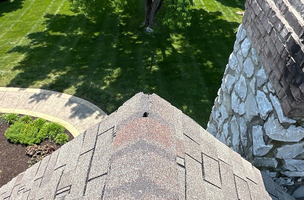 Damaged ridge cap shingles along the peak of a roof