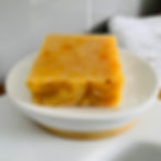 Orange coloured square soap bar on a white soap dish.