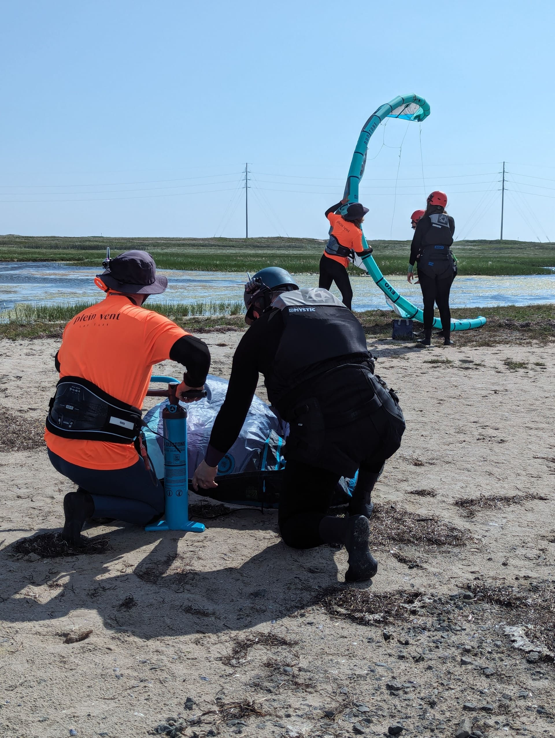 Instructeur de Plein Vent les îles préparant un kite pour un cours privé aux Îles-de-la-Madeleine, avec un cours en duo en arrière-plan montrant la manipulation de l'aile.