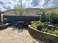 Sunny patio area at Shepherd's Rest Inn with flower beds, stone walls and outdoor tables overlooking the hills of Todmorden.