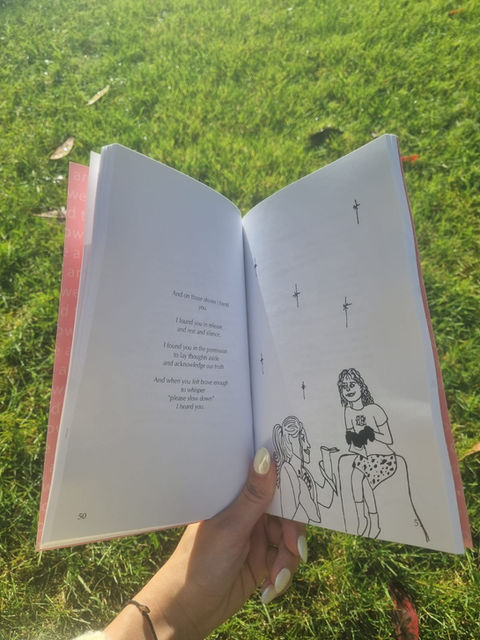An open copy of the book against the background of grass. The page contains a short poem that is not readable and an illustration of a grown woman holding her hand out to a small child.