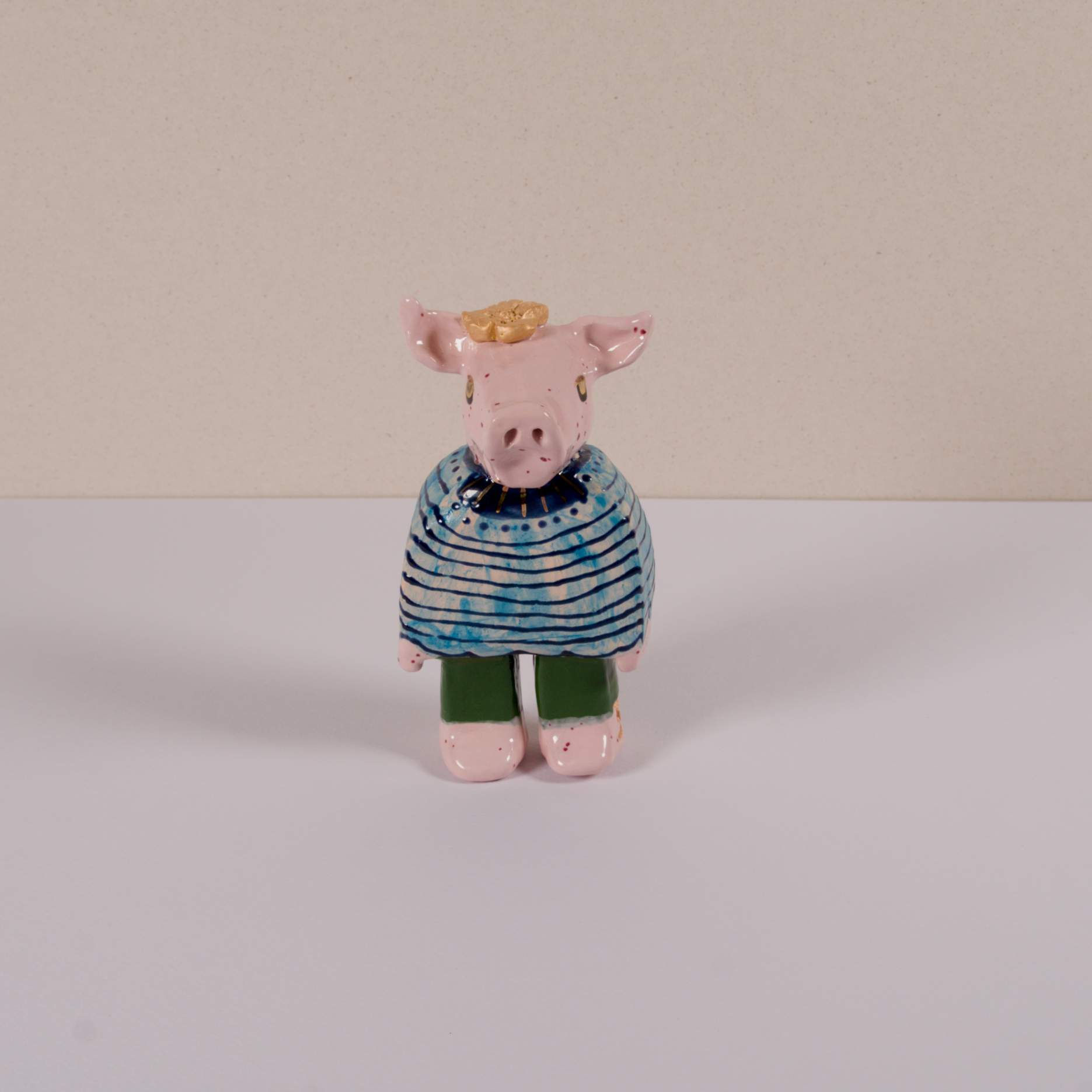 Figur eines Schweins in einem Pullover und grünen Hosen, stehend.