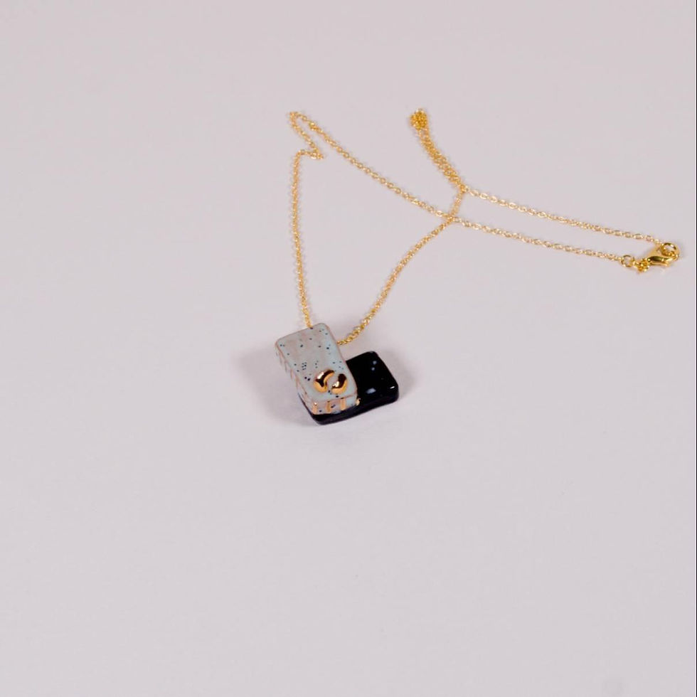 Miniaturbild: Halskette mit Anhänger, goldene Kette, schwarzer und silberner Anhänger auf Weiß