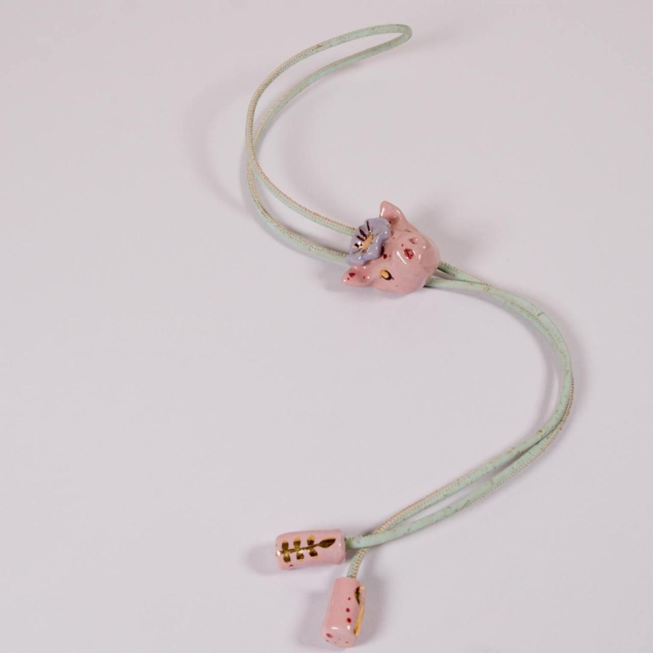 Rosa Halskette mit Blumenmotiv und zwei passenden Anhängern; auf weißem Hintergrund.