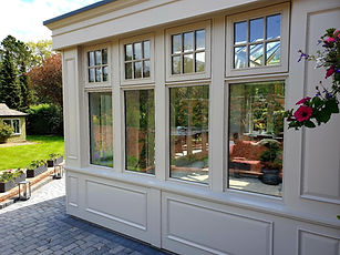 Orangery hardwood windows freshly painted and installed by skilled craftsmen, adding elegance and charm to the architecture with their rich wood tones and meticulous finishing.