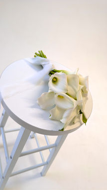 A bridal bouquet of white calla lilies on a stool