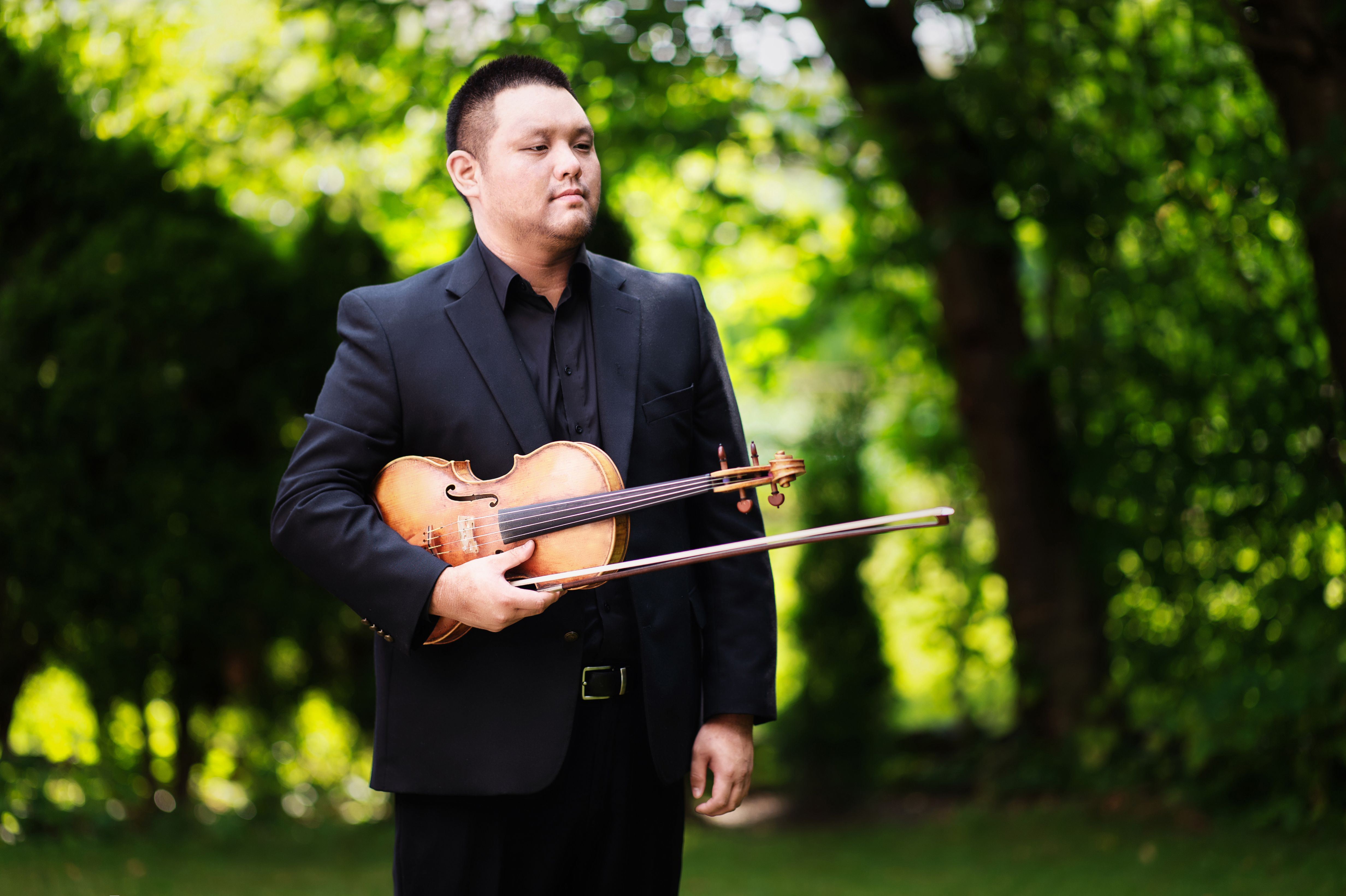 Samuel Choi holding a violin outdoors