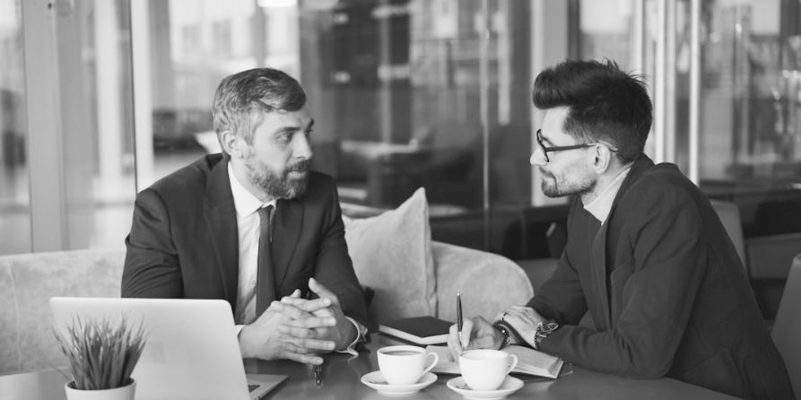 A professional man getting expert resume feedback from a recruiter to fix resume red flags for senior leaders that are holding back his job search.