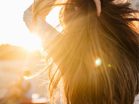 Female on the beach pulling back her long hair in the sun
