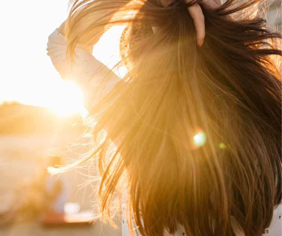 Female on the beach pulling back her long hair in the sun