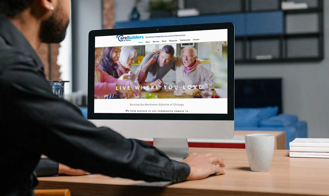 Man sitting at desktop computer with the vibrant CareBuilders at Home website homw page pulled up on screen.