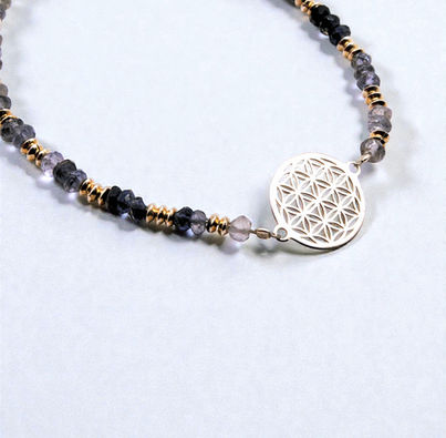 Fleur de vie centrale en argent 925/000 pour ce bracelet fait sur place en cordiérite. Monté sur un câble acier grâce à notre savoir-faire artisanal.