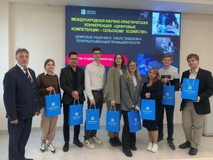 Группа людей стоит перед экраном, держа синие сумки.