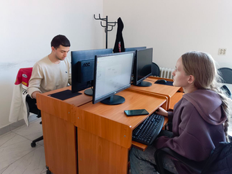 За столом сидят мужчина и женщина, оба работают на компьютерах, погруженные в свои дела.