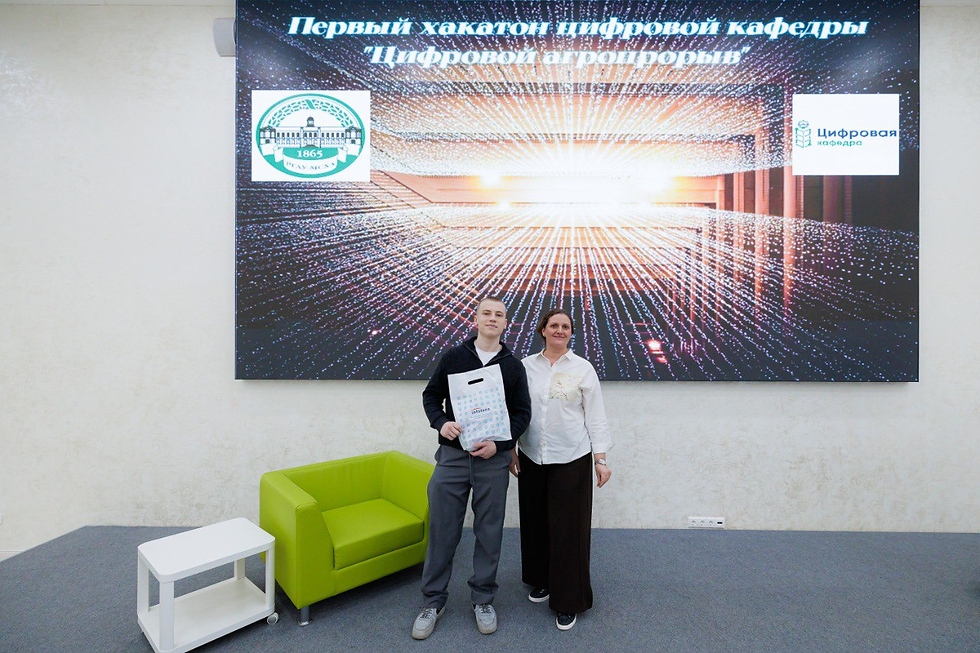 «Два участника позируют для фото в помещении после хакатона; один держит подарочный пакет.