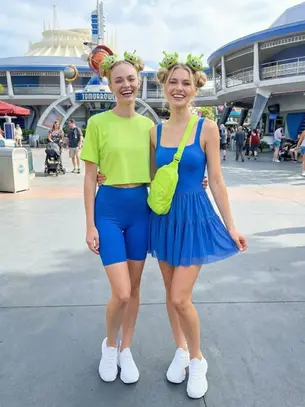 Family in coordinated Pooh and Friends Disney park outfits — mom in Tigger, daughter in Piglet, dad in Pooh — coordinated family outfits for pictures at Disney World