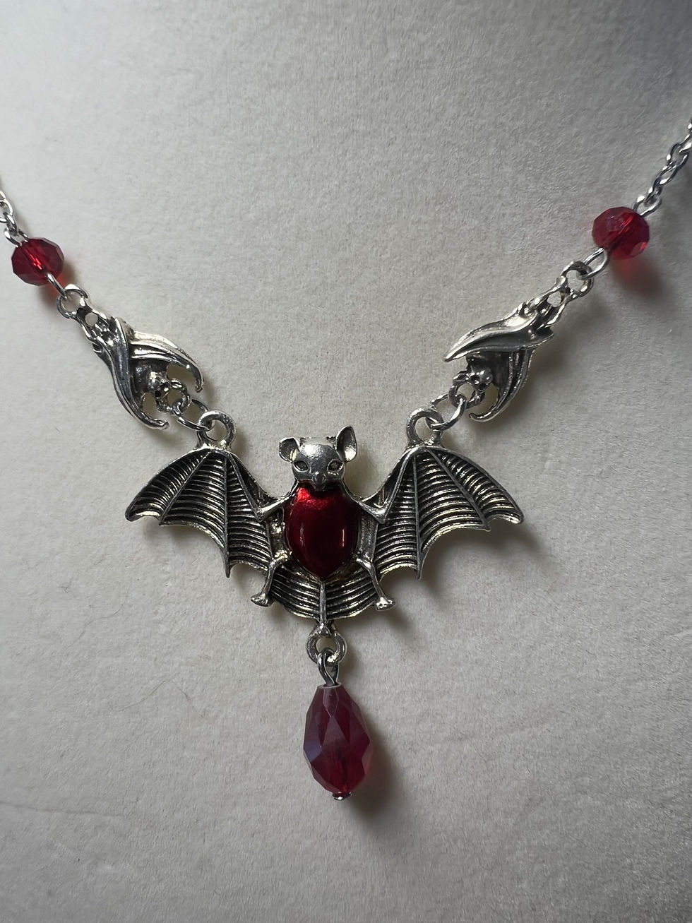 Thumbnail: Gothic silver bat necklace with red beads and dangling red teardrop close up