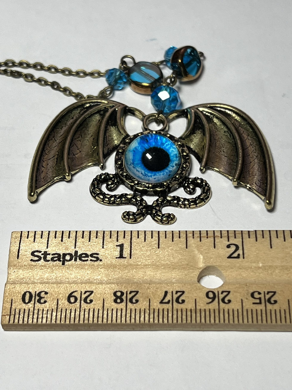 Thumbnail: Handmade steampunk necklace featuring a large brass winged pendant with a blue dragon eye cabochon width