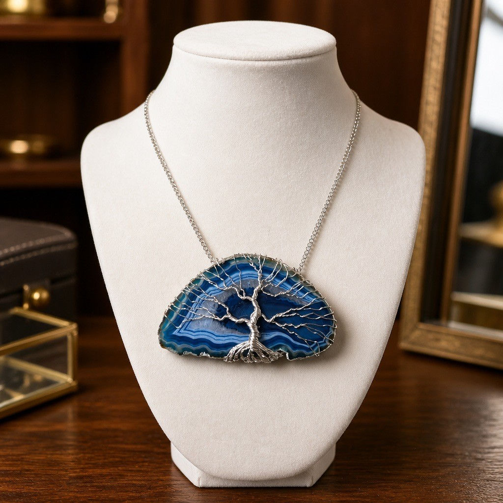 arge handmade blue agate slice pendant featuring multiple shades of blue banding with a tree of life on face