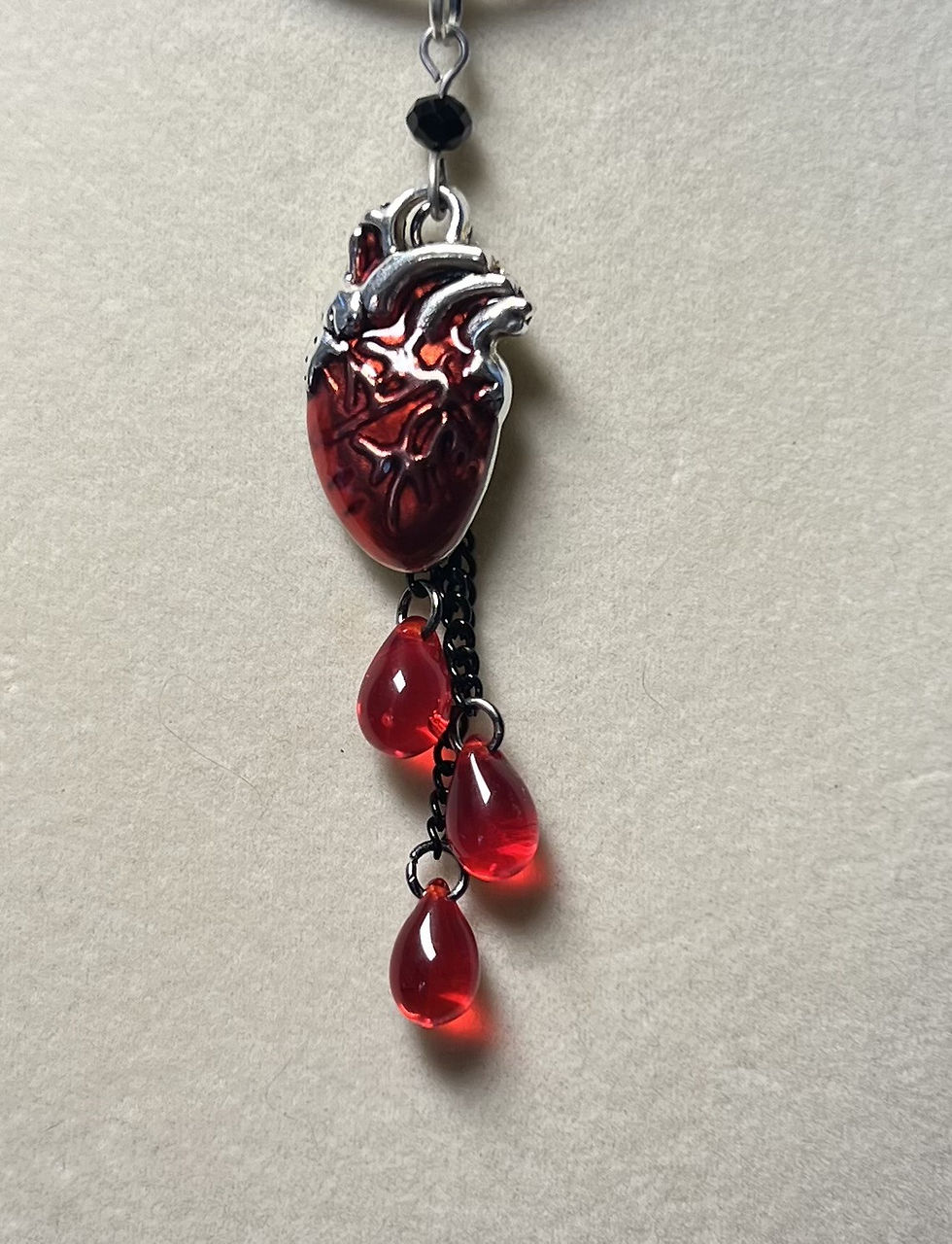 Thumbnail: Close-up of a handmade gothic necklace featuring an anatomical heart charm and cascading red bead accents on a black waxed co