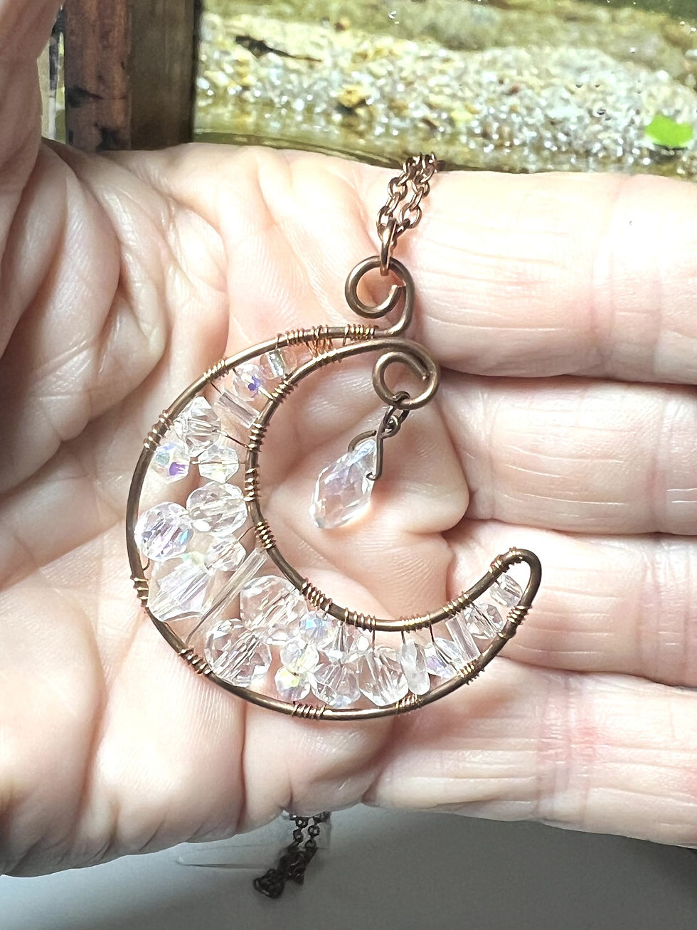 Thumbnail: Copper wire wrapped crescent moon pendant necklace with clear crystal beads and dangling crystal charm in hand