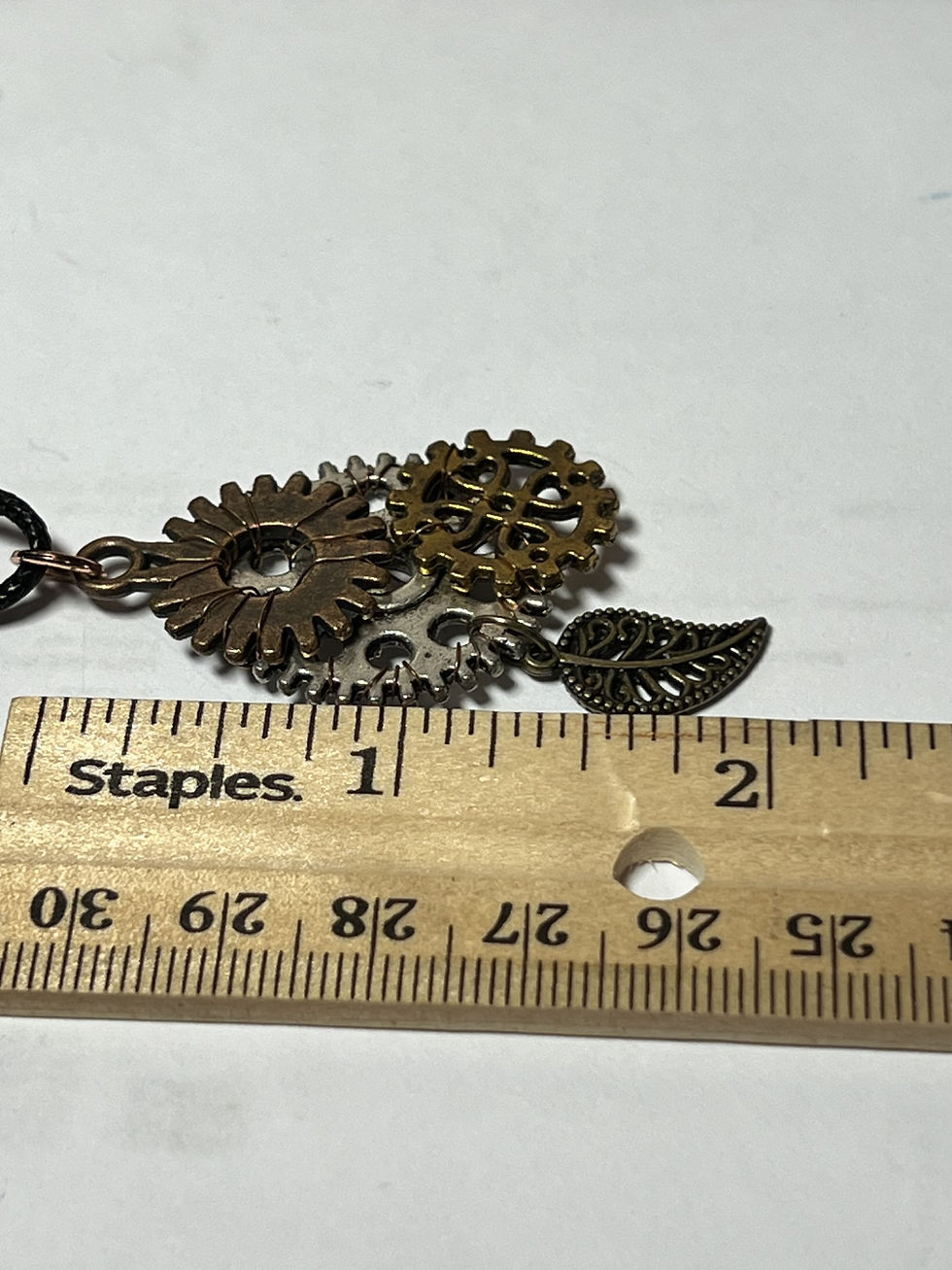 Thumbnail: Handmade steampunk necklace featuring a large silver gear decorated with copper and gold tone gears and bronze leaf length