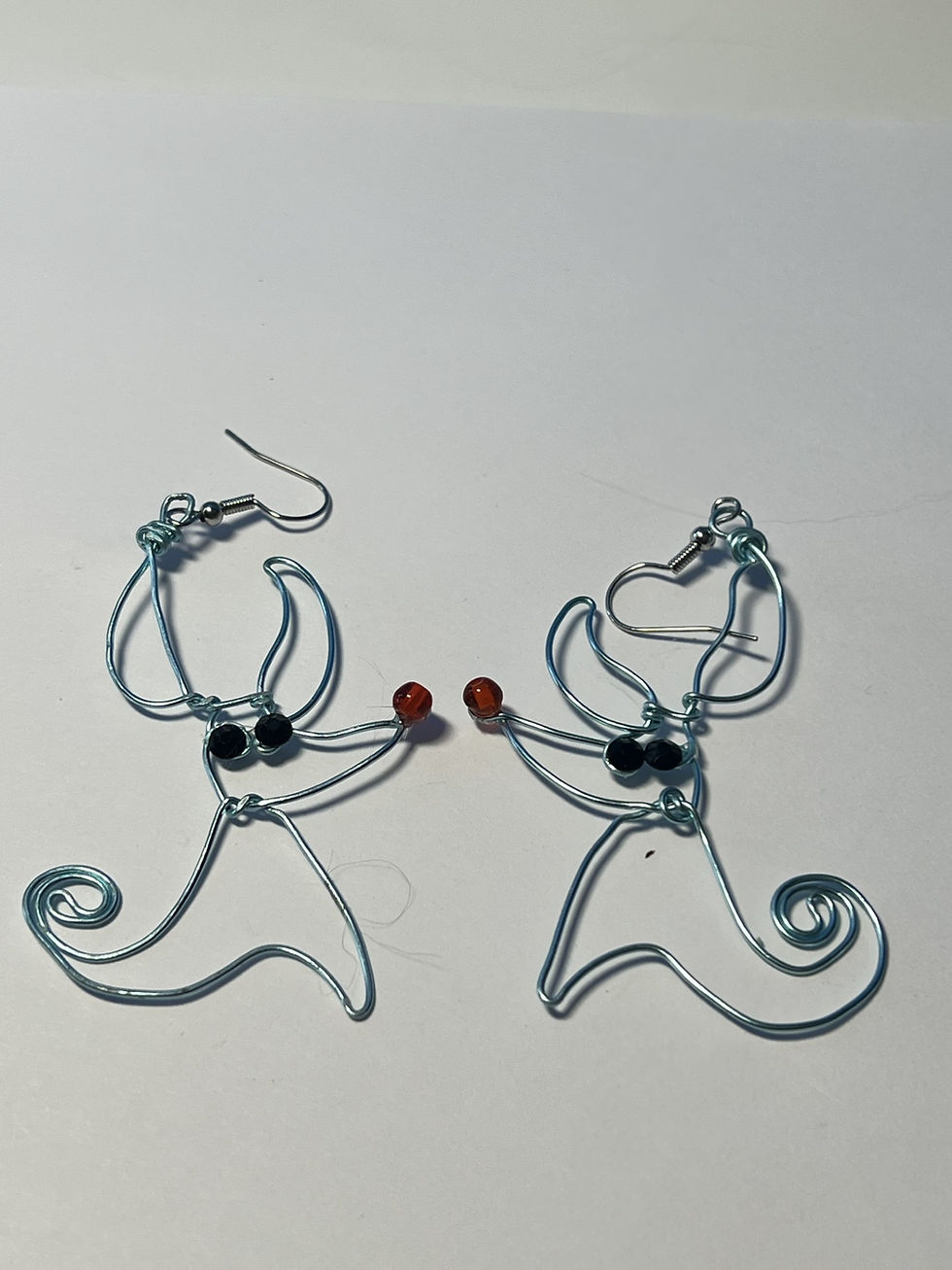 Thumbnail: Light blue wire wrapped Zero ghost dog earrings with black rhinestone eyes and orange bead nose closeup