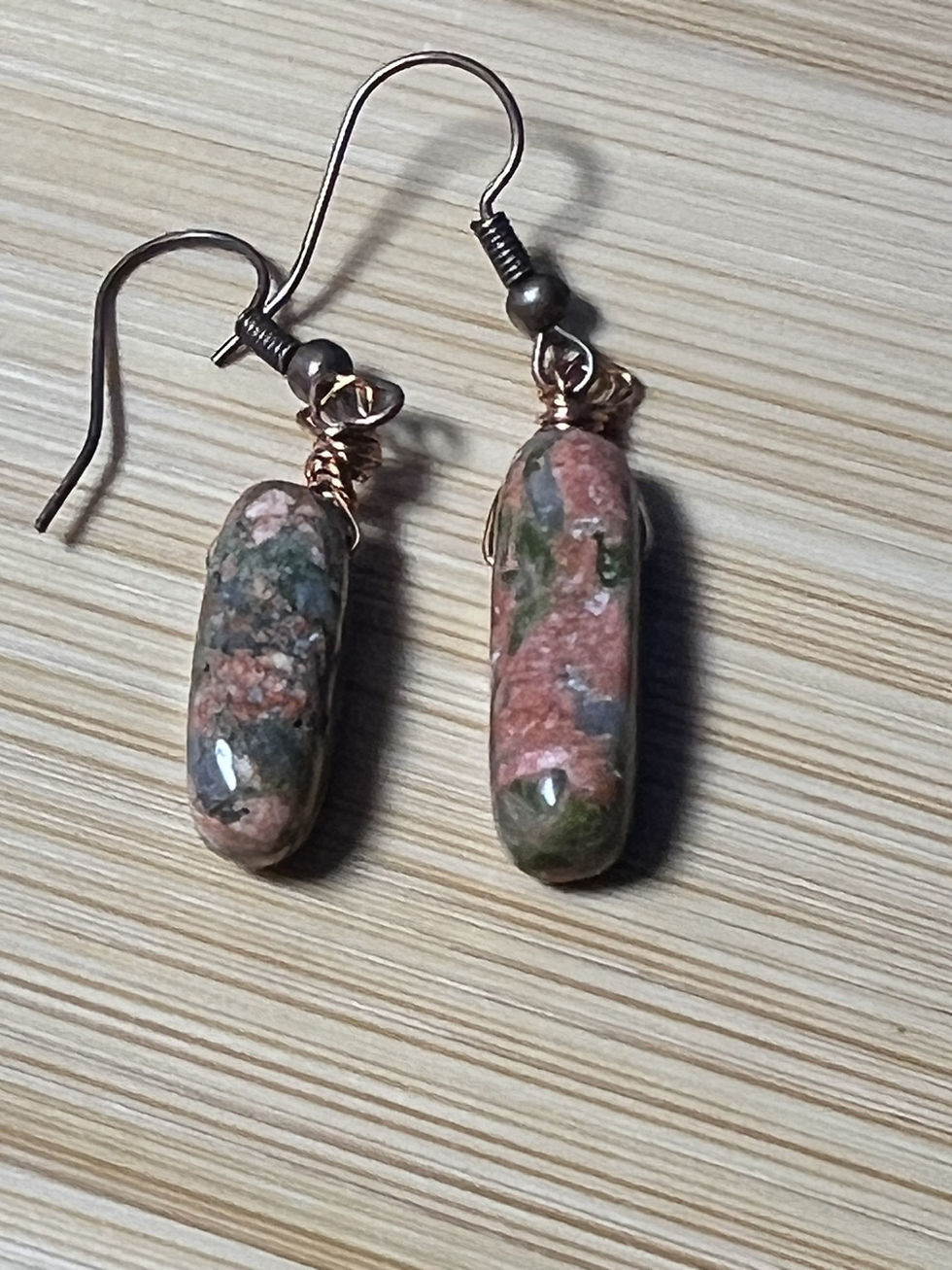 Thumbnail: Handmade unakite crystal earrings wrapped in copper wire with green and pink natural tones closeup