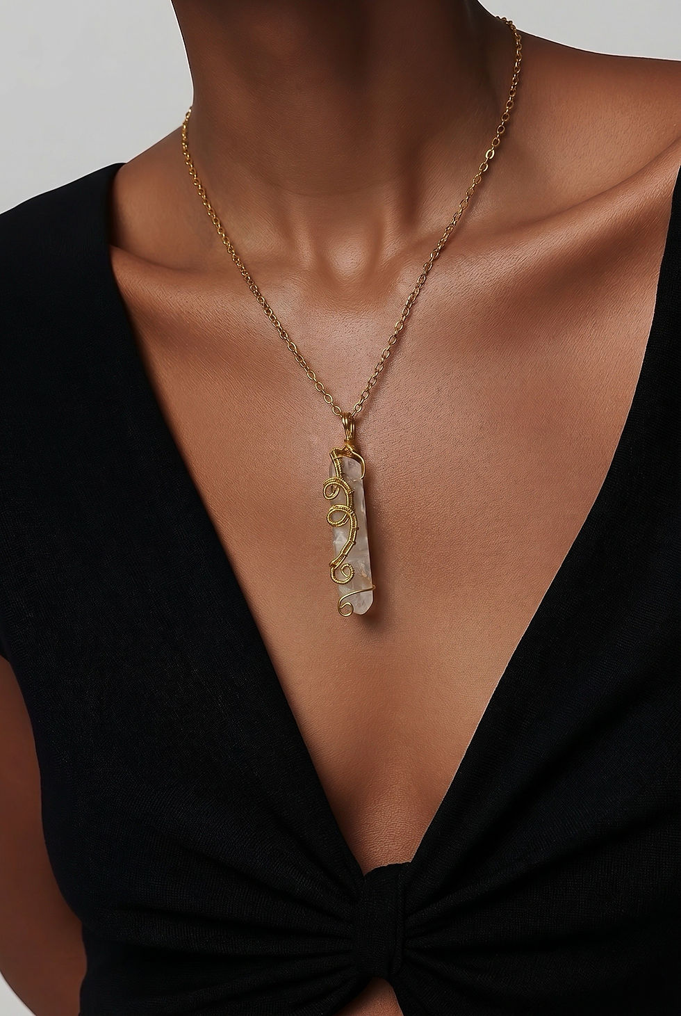 Ornate wire wrapped white quartz crystal pendant necklace with intricate metal detailing on model