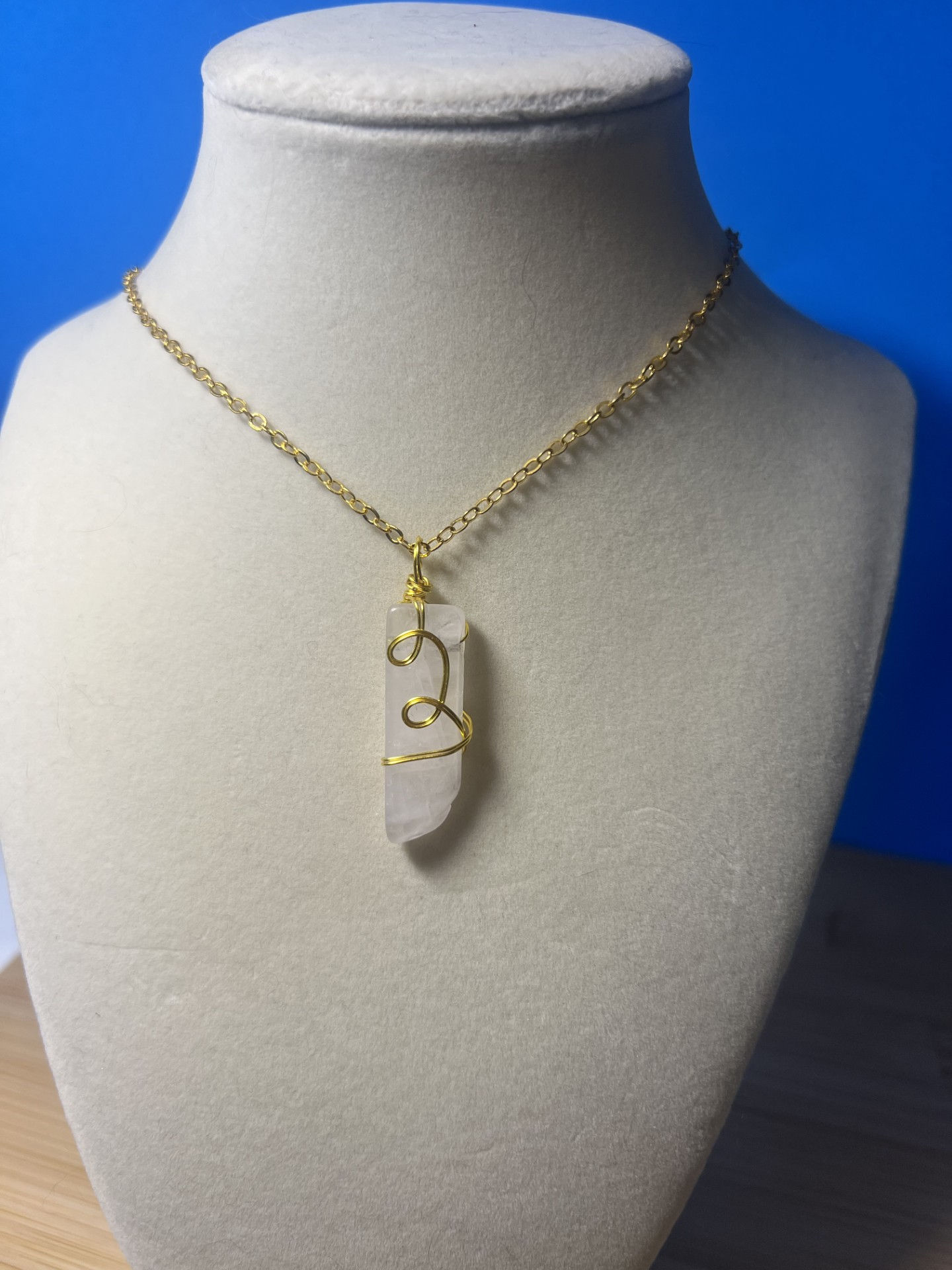 Wire wrapped clear quartz crystal necklace with gold wire wrapping forming a handmade pendant