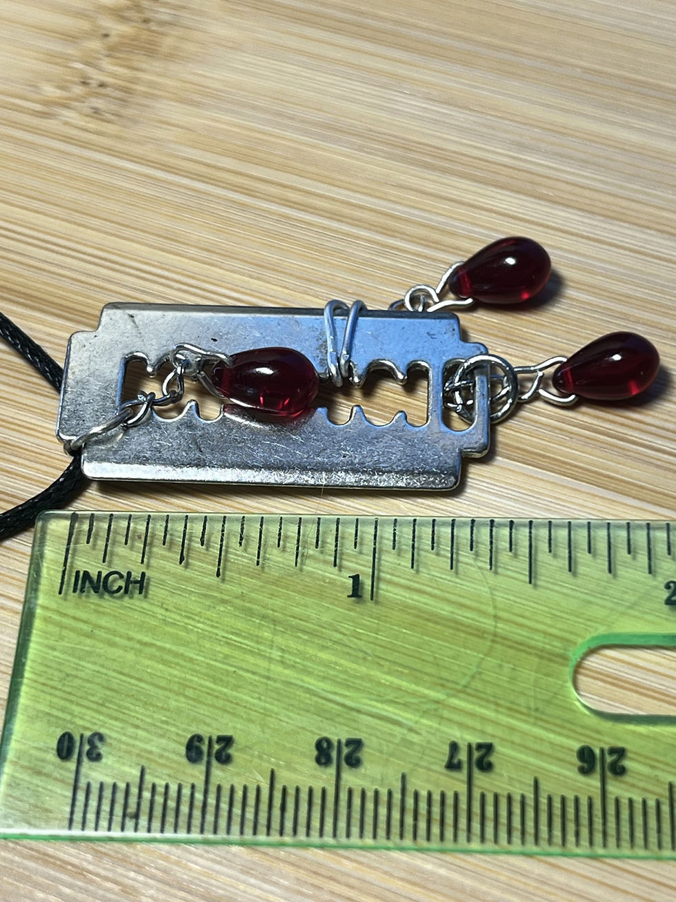 Thumbnail: Gothic razor blade necklace with three red teardrop bead dangles suspended from a waxed cord necklace length