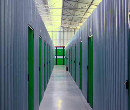 Corredor com boxes individuais verdes no self storage Cubico