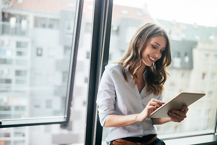 Attractive-businesswoman-using-a-digital-tablet-while-standing-in-front-of-windows-1164863