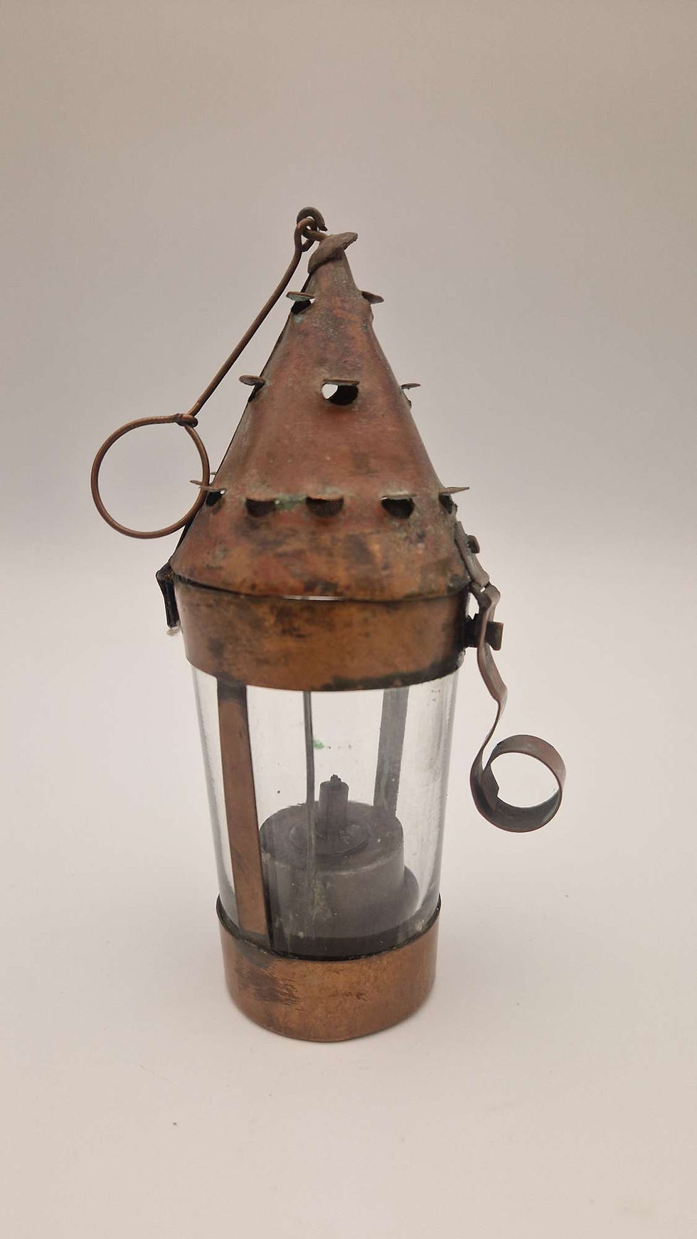 A vintage miniature oil lantern from the early 1900s, featuring a classic design with a glass enclosure, metal handle, and brass accents, typical of early 20th-century portable lighting devices