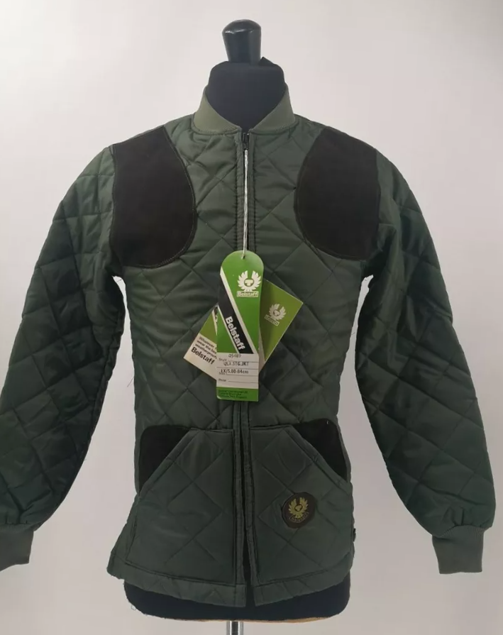 Thumbnail: giacca trapuntata di stile vintage, prodotta da Belstaff negli anni '70. La giacca è di colore verde, con una finitura robusta e resistente tipica di quegli anni. Presenta un design classico con imbottitura trapuntata, cappuccio integrato e dettagli funzionali che richiamano lo stile outdoor e avventuroso di quegli anni. È ideale per chi cerca un capo di abbigliamento retrò con un tocco di stile e praticità.